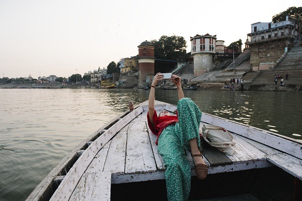 Femme occidentale allongée sur un bateau prenant des selfies à Varanasi